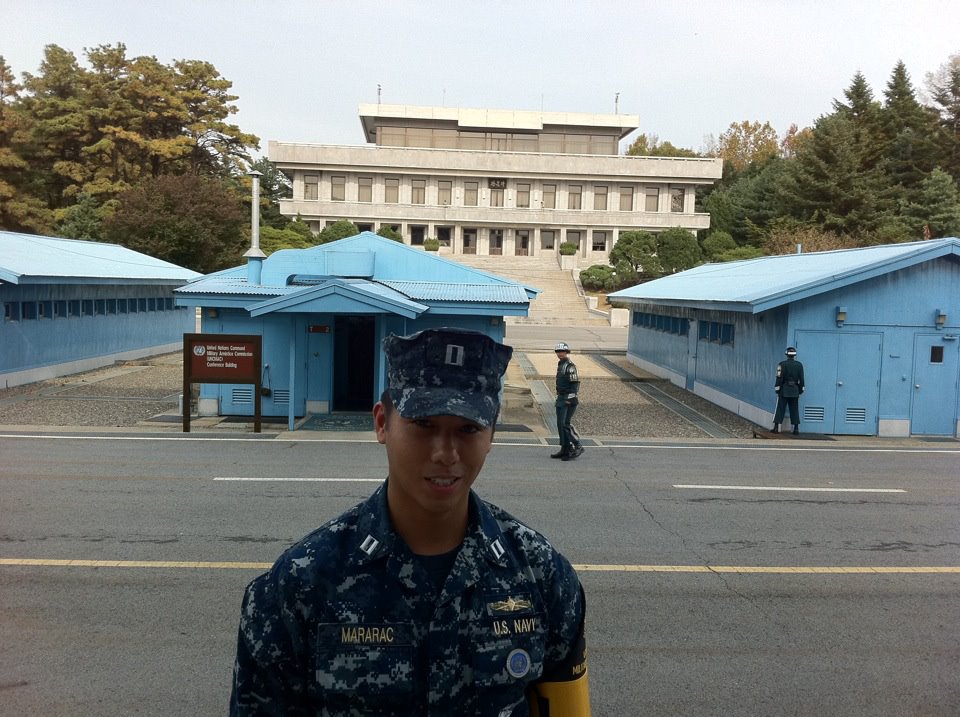 Standing on the South Korean side of the Joint Security Area facing North Korea with the blue buildings and Panmungak building in the background. (image links to wikipedia about JSA)